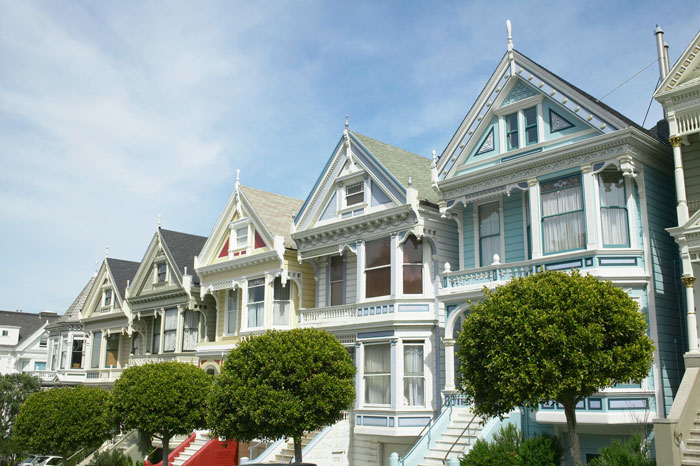 Row of Victorian houses in a neighborhood with neatly trimmed lawns highlighting HOA grass height dispute and neighbor retaliation.