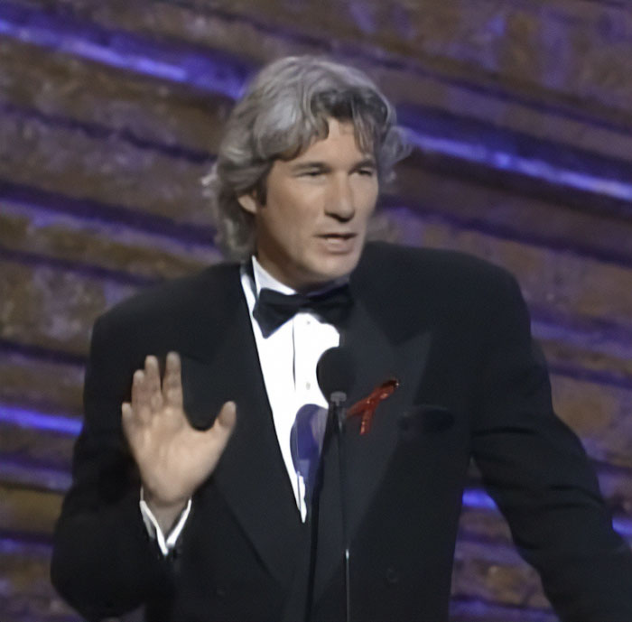 Richard Gere speaking at an event, wearing a black tuxedo and addressing the audience about Oscars ban controversy.