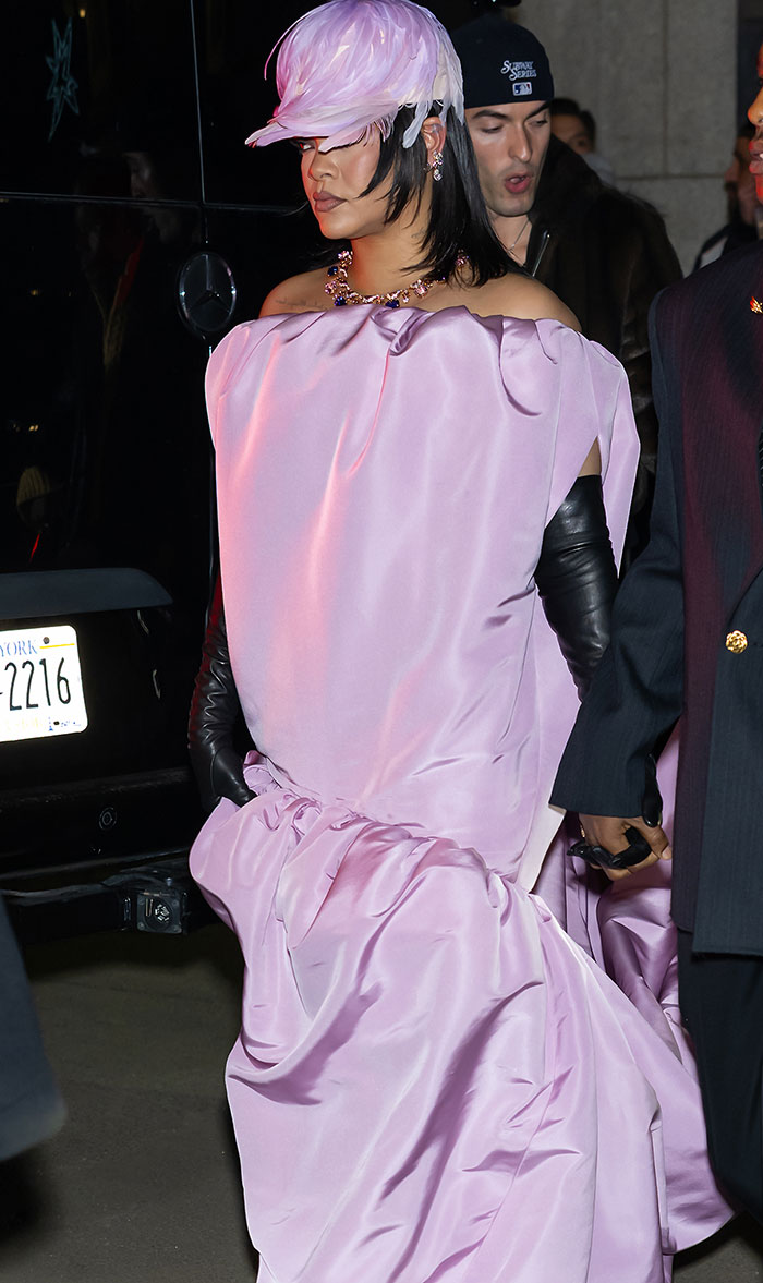 Rihanna in a voluminous pink gown and feathered headpiece, sparking wild reactions on the red carpet with her look.