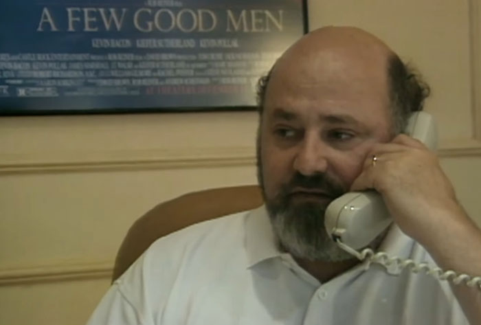 Man with beard and balding hair holding a phone, related to son eyed as person of interest in LA home case.