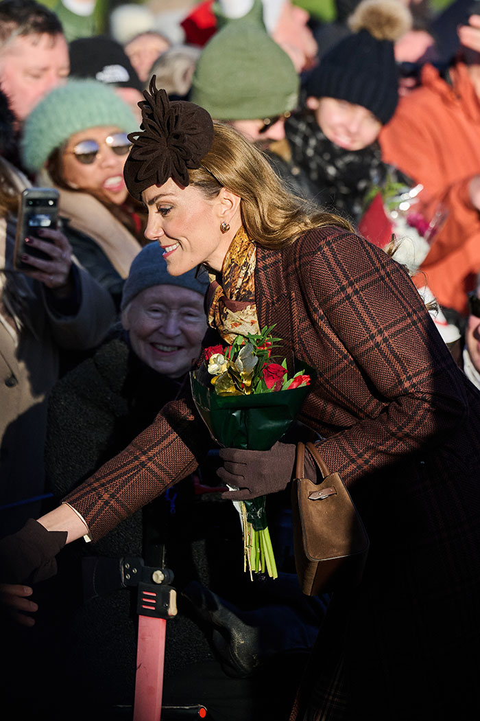 Kate Middleton smiling and holding flowers during Christmas appearance, sparking conversations about her scar and health.