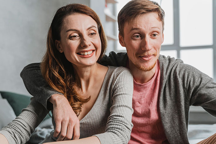 New mom politely declines family vacation after brother insists his pit bull is safe around her baby, smiling together indoors.