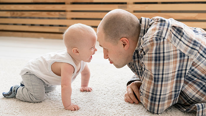New mom interacting with baby at home, highlighting concerns about pit bull safety around her infant during family vacation.
