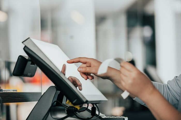 Person using a touchscreen cash register and holding a receipt, illustrating a glitch in the system in a retail environment.
