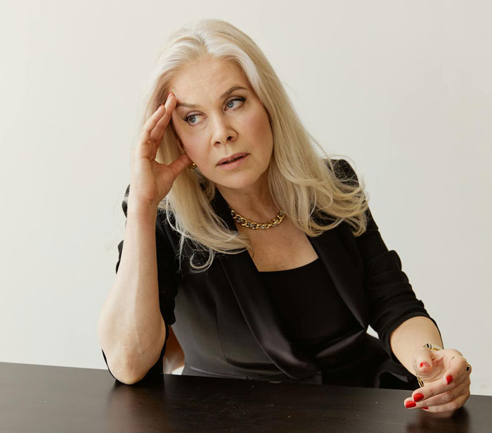 Middle-aged woman with long blonde hair and black outfit looking stressed, related to barefoot spiritual advisor chaos at Thanksgiving.