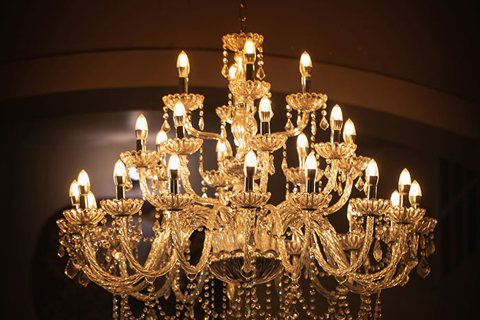 Ornate crystal chandelier with lit bulbs, showcasing elegance and intricate design in warm lighting.