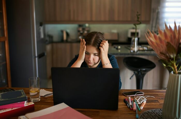 Young woman stressed at laptop in kitchen, reflecting on what happened to the most likely to succeed with plot twists.