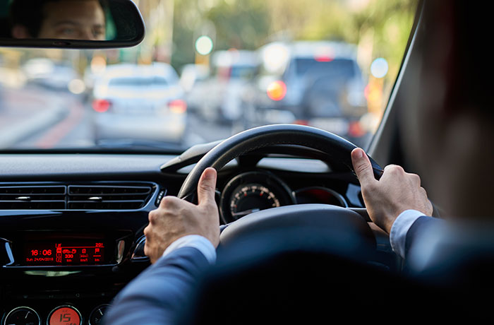 Person driving a car with hands on the steering wheel, illustrating psychological cheat codes for easier social life skills.