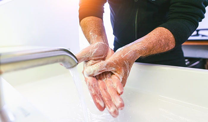 Person washing hands with soap and water at sink, showing serious hygiene amid panic on his face concept.