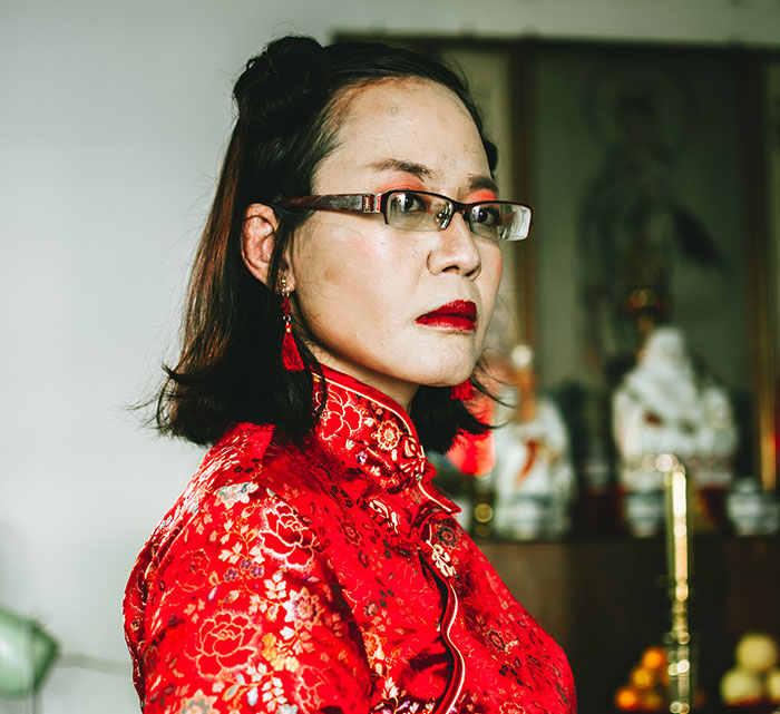 Woman in red traditional dress with glasses showing panic on her face, capturing a serious moment of emotional reaction