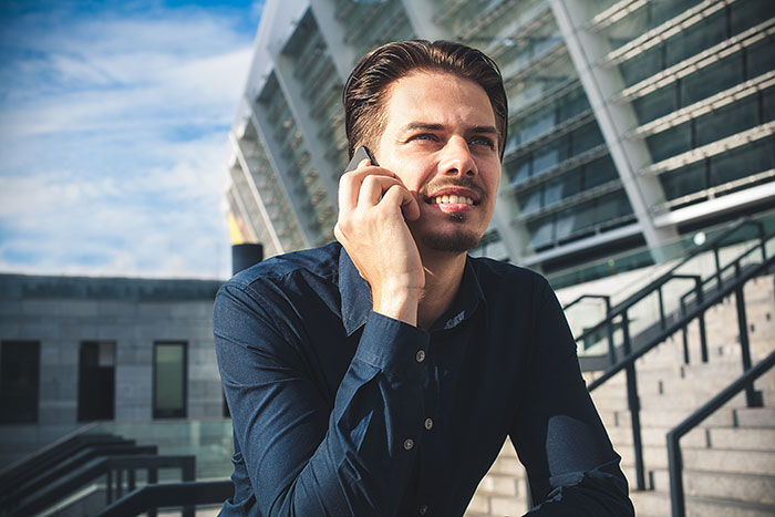 Young man showing panic on his face while talking on phone outside a modern building in bright daylight