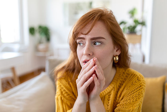 Woman in a yellow sweater looking thoughtful and anxious while reflecting on personal experiences that changed beliefs