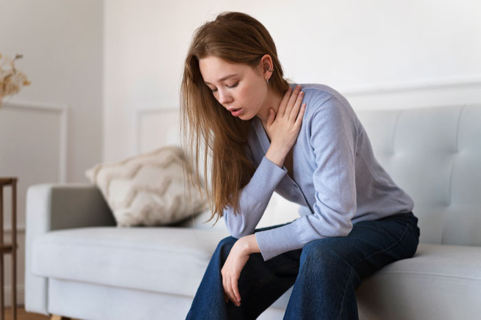Young woman sitting on a sofa looking distressed, reflecting on things people only believe once it happens to them.