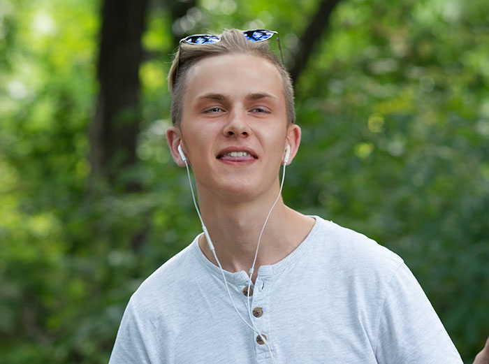 Young man with earbuds and sunglasses sharing things people only started to believe once it happened to them outdoors.