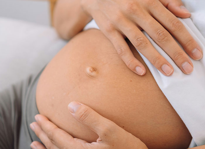 Close-up of hands gently resting on a pregnant belly, illustrating human body and mammalian dive reflex concepts.