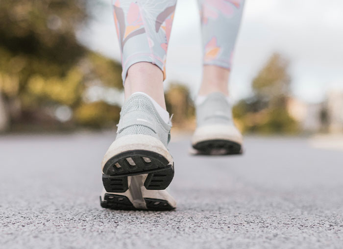 Close-up of a person walking on pavement wearing gray sneakers, illustrating aspects of the human body’s mammalian dive reflex.