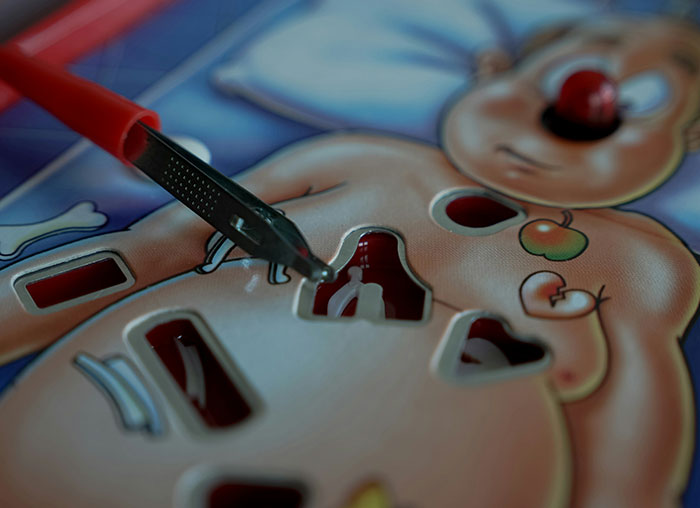 Close-up of a surgical game showing human body parts being carefully removed with a red-handled tool illustrating human body facts.