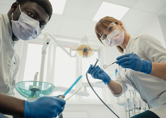 Two medical professionals in masks and gloves preparing dental tools, highlighting wild and funny post-anesthesia acts moments.