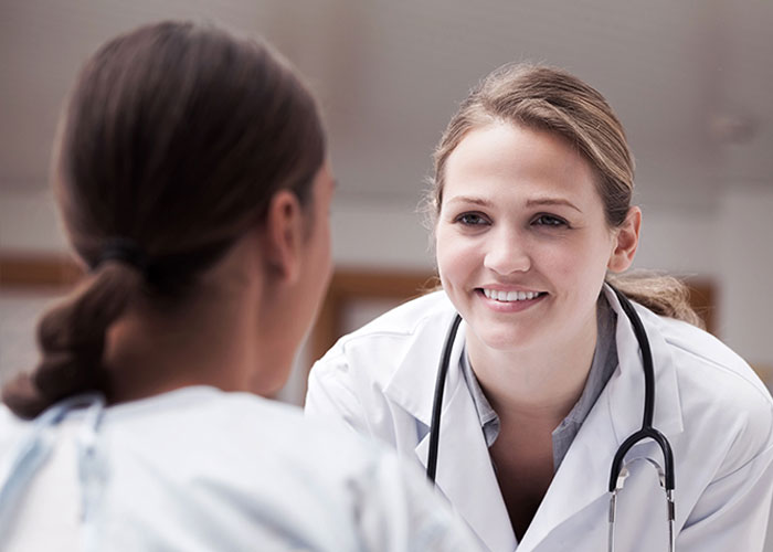 Female doctor attentively speaking with a patient, highlighting post-anesthesia acts doctors and nurses encounter.
