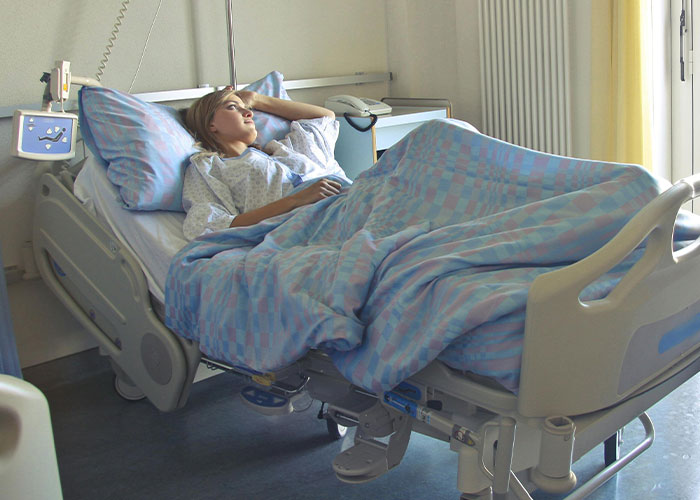 Patient lying in hospital bed recovering from anesthesia, illustrating post-anesthesia acts doctors and nurses encounter.