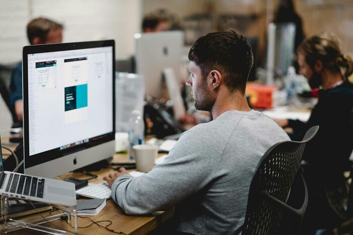 Man focused on computer screen in an office setting, representing people online sharing stories about small decisions.