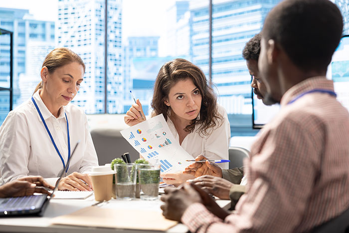 Business team analyzing charts and discussing subtle red flags that indicate job security concerns in an office setting. Business team analyzing charts and discussing subtle red flags that indicate job security concerns in an office setting.