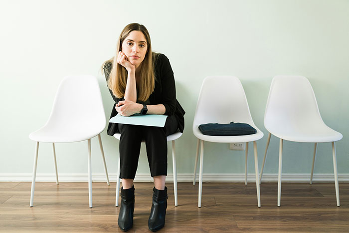 Young woman sitting nervously in an empty waiting room, highlighting subtle red flags of job insecurity. Young woman sitting nervously in an empty waiting room, highlighting subtle red flags of job insecurity.