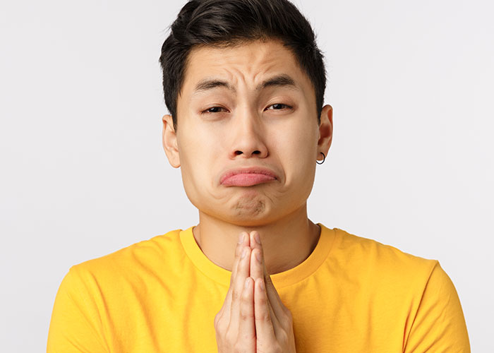 Young man in yellow shirt pleading with a distressed expression, relating to a cruel prank and family reaction.