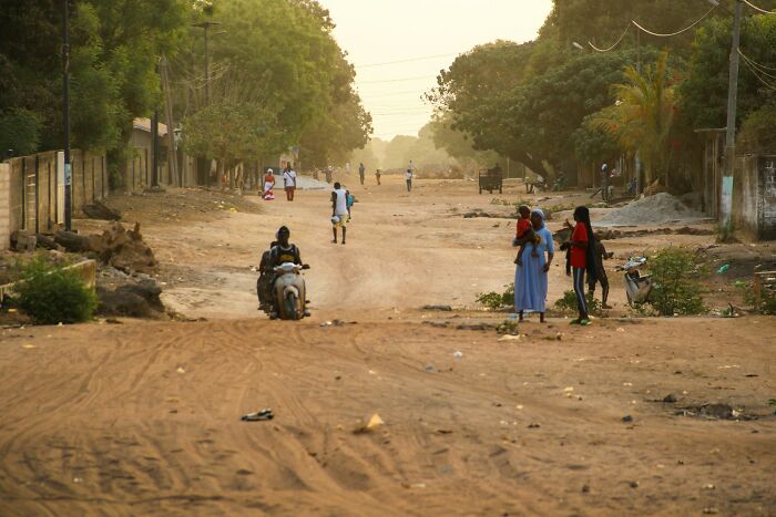 People in a dusty street instinctively sensing something was wrong as they walk and stand in groups at dusk.