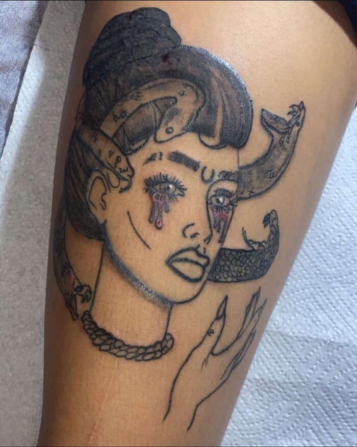 Tattoo of abstract woman with horns and tears on leg, showcasing one of the worst tattoos shared in online groups.