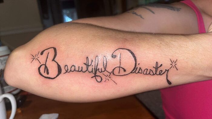Tattoo on forearm reading Beautiful Disaster in cursive style, featured in worst tattoos online group collection.