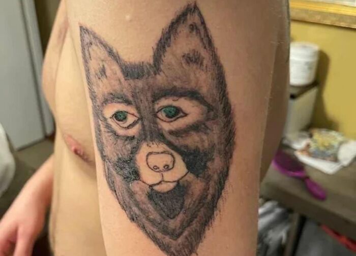 Tattoo of a wolf with human-like eyes on a person's arm, showing one of the worst tattoos featured in a cringe group.