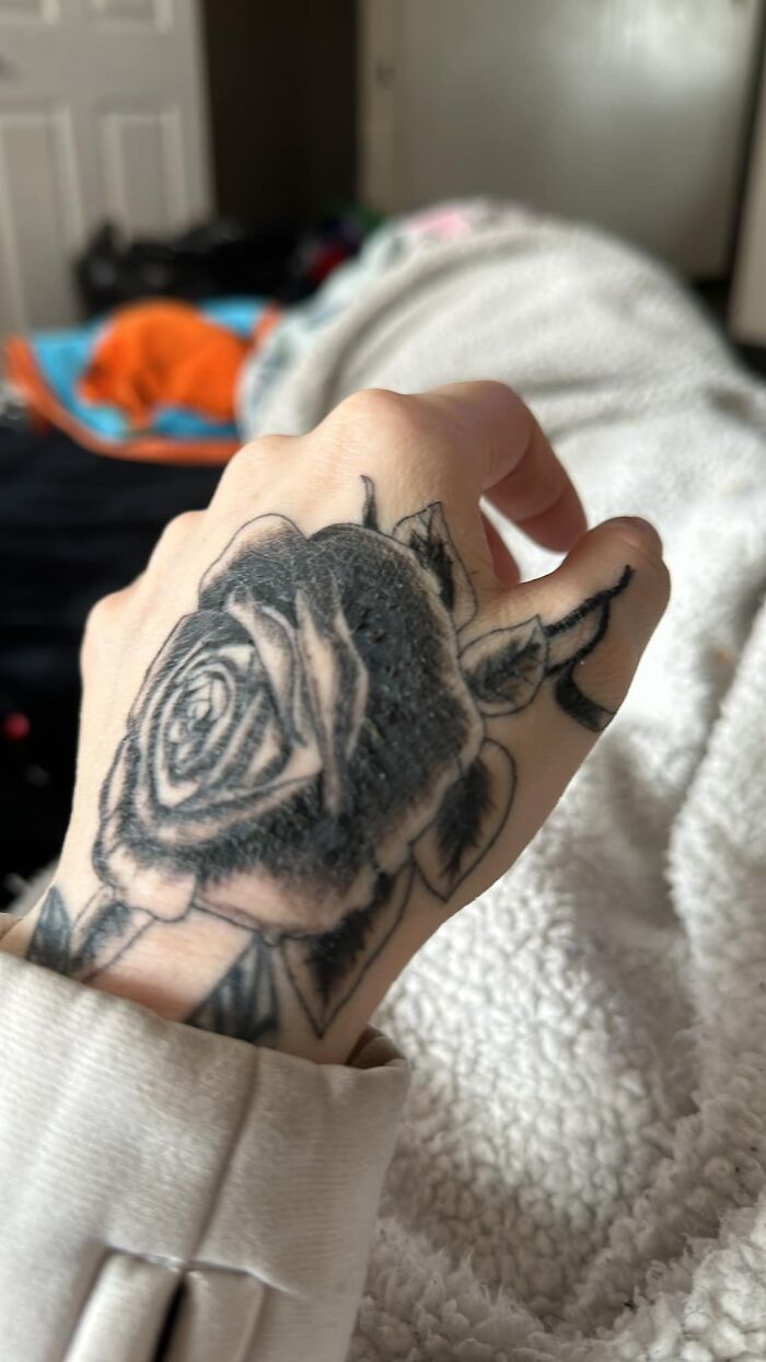 Black and grey rose tattoo on hand showing rough texture, featured in a collection of worst tattoos making members cringe.