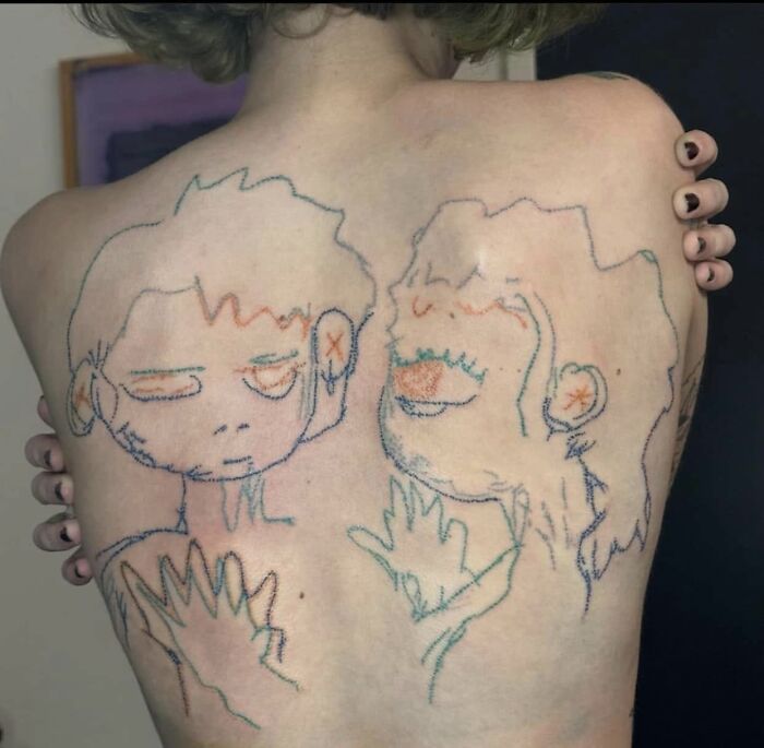 Person with a large, poorly drawn tattoo of two cartoon faces on their back, showcasing worst tattoos in an online group.