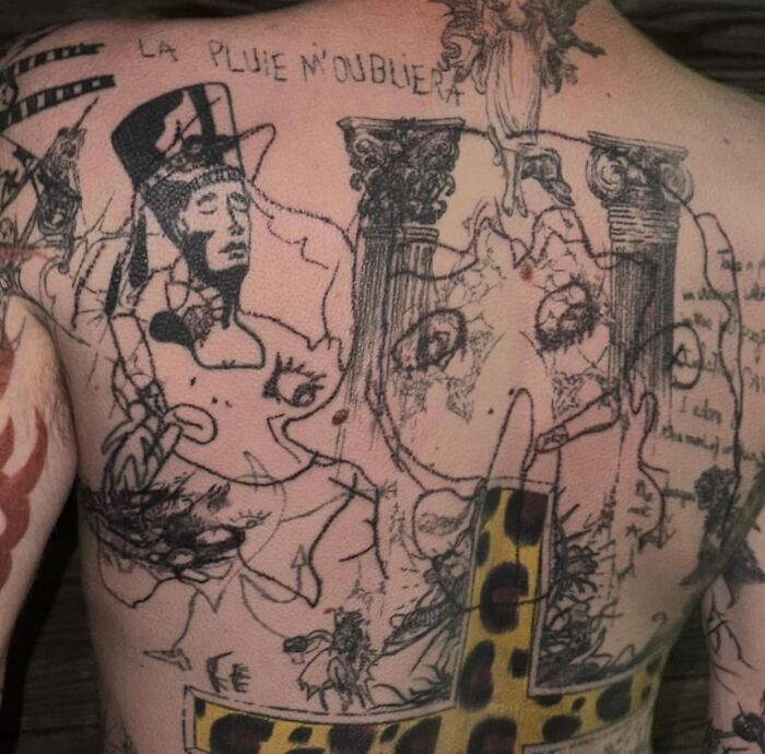 Back tattoo with sketch-like drawings and a large leopard-print cross, showcasing some of the worst tattoos made members cringe.
