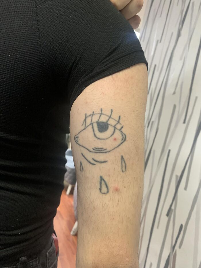 Tattoo of a crying eye with simple lines on a person's upper arm in an online worst tattoos group.
