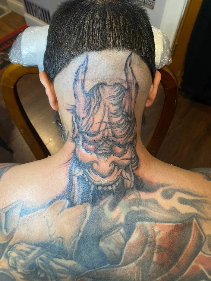 Tattoo of a demonic face on the back of a person's head, showcasing one of the worst tattoos in an online group dedicated to bad tattoos.