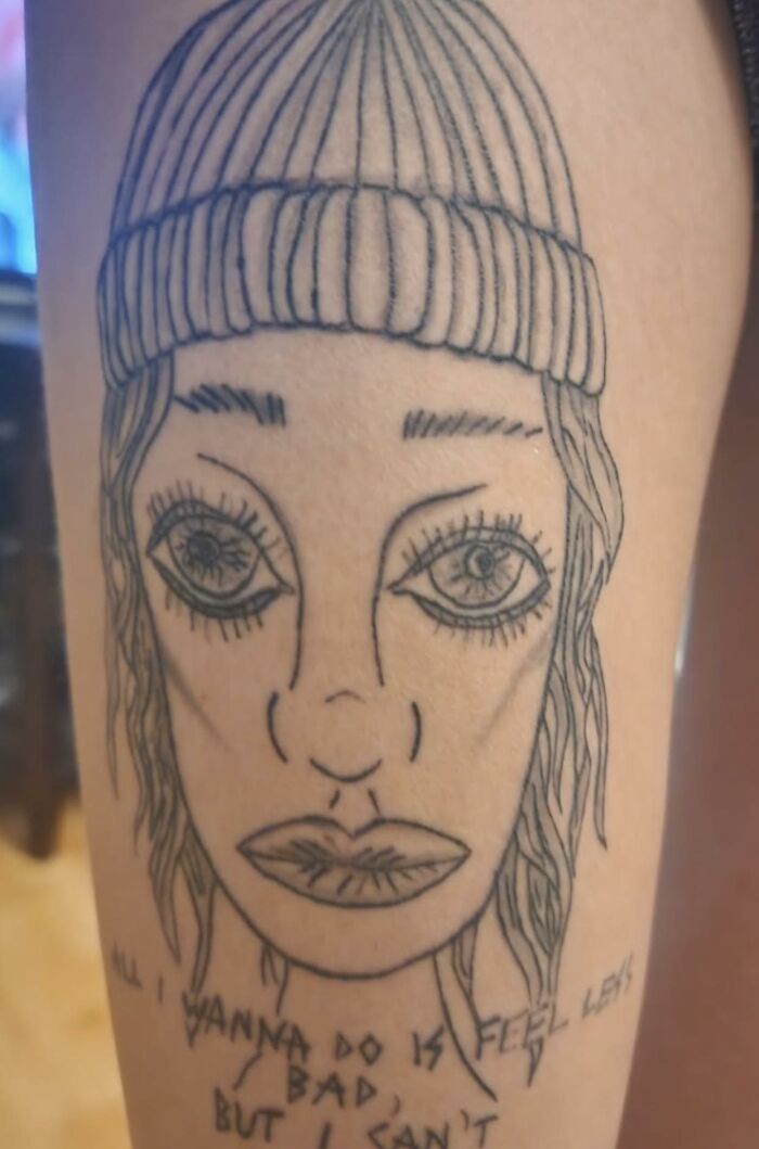 Tattoo of a distorted face wearing a beanie with uneven features, representing one of the worst tattoos shared online.