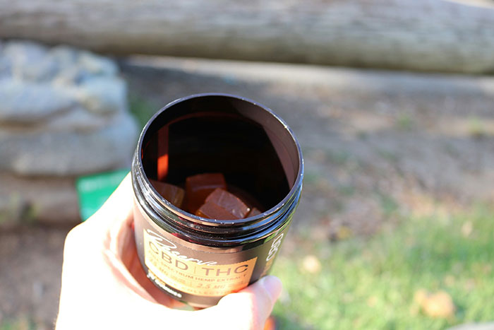 Open container of CBD THC gummies held outdoors, related to mom calling 911 after kids ate her gummies incident.