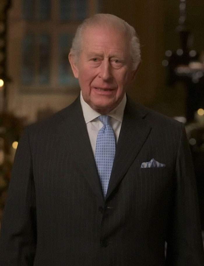 Older man in a dark suit and light blue tie delivering a formal message related to Meghan Markle and Prince Harry split rumors