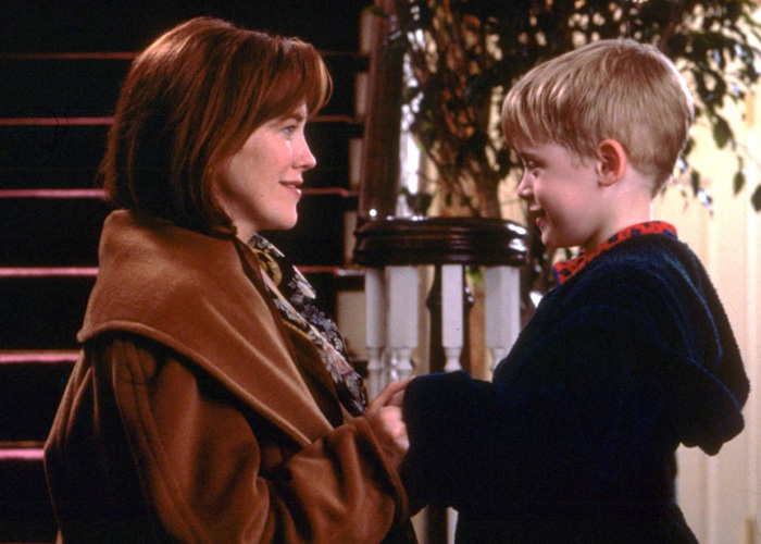 Scene from Home Alone movie showing a woman and young boy holding hands in a warmly lit home setting. Scene from Home Alone movie showing a woman and young boy holding hands in a warmly lit home setting.