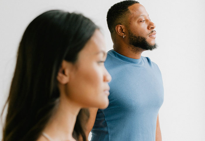 A focused woman and a thoughtful man standing apart, representing female roasts that impact men deeply.