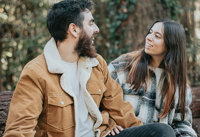 Woman and man outdoors laughing together during a casual moment, illustrating female roasts hitting men hard.