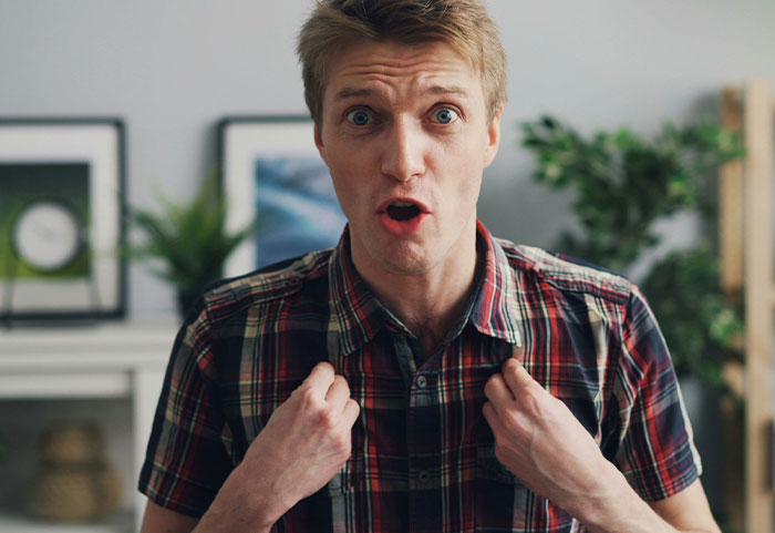Young man in a plaid shirt reacting with surprise, illustrating impact of female roasts on men.