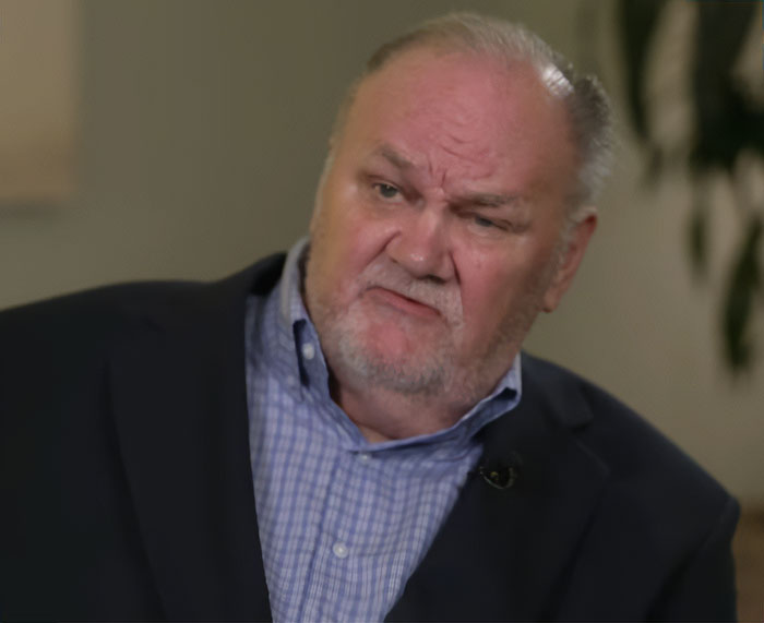 Older man with a serious expression wearing a checkered shirt and dark blazer during an interview about Meghan Markle controversy. Older man with a serious expression wearing a checkered shirt and dark blazer during an interview about Meghan Markle controversy.