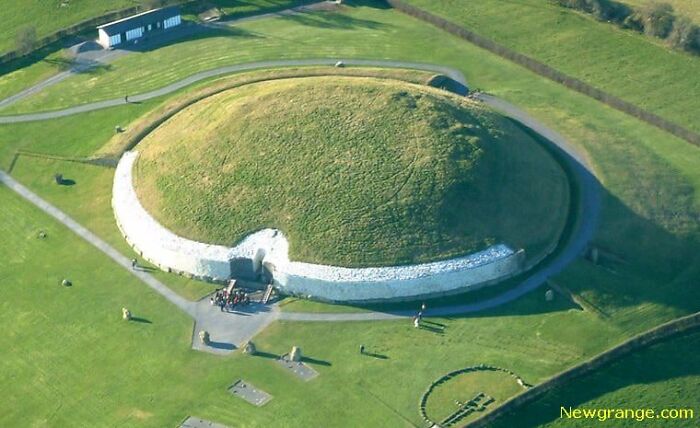 Aerial view of Newgrange, an ancient real place that looks AI generated with green grass and stone structures.