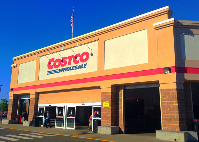 Costco Wholesale store exterior under clear blue sky with customers entering, highlighting interesting facts and learning moments.