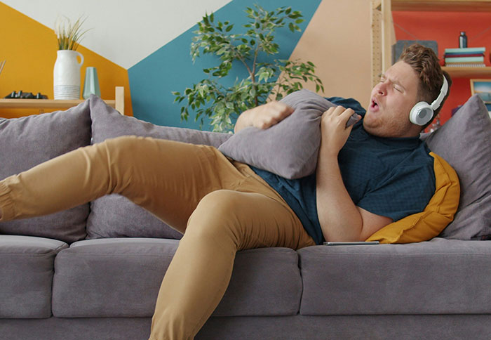 Man relaxing on couch with headphones, illustrating dad privileges in parenting shared by moms in a candid moment.