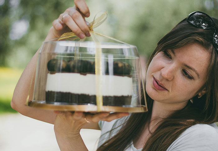 Woman holding a cake in a clear container, reflecting on dad privileges shared by 61 moms in parenting experiences.