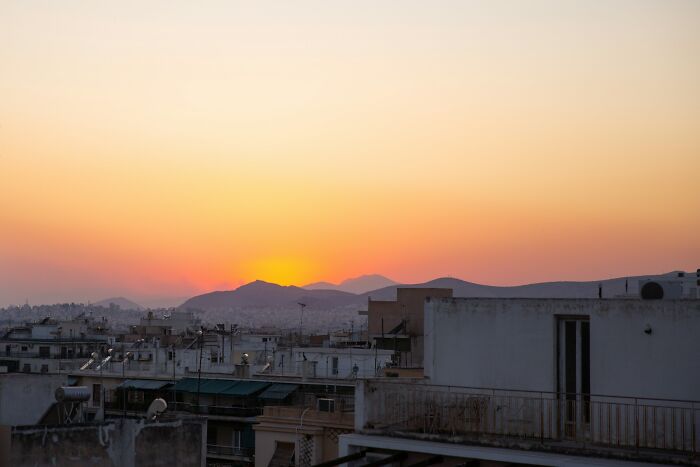 Sunset over a Greek village with rooftops and mountains in the background, capturing village life atmosphere.